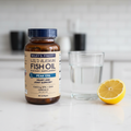 AI-generated contextual image of Wiley's Finest Peak EPA Wild Alaskan Fish Oil 90 Softgels beside water and lemon
