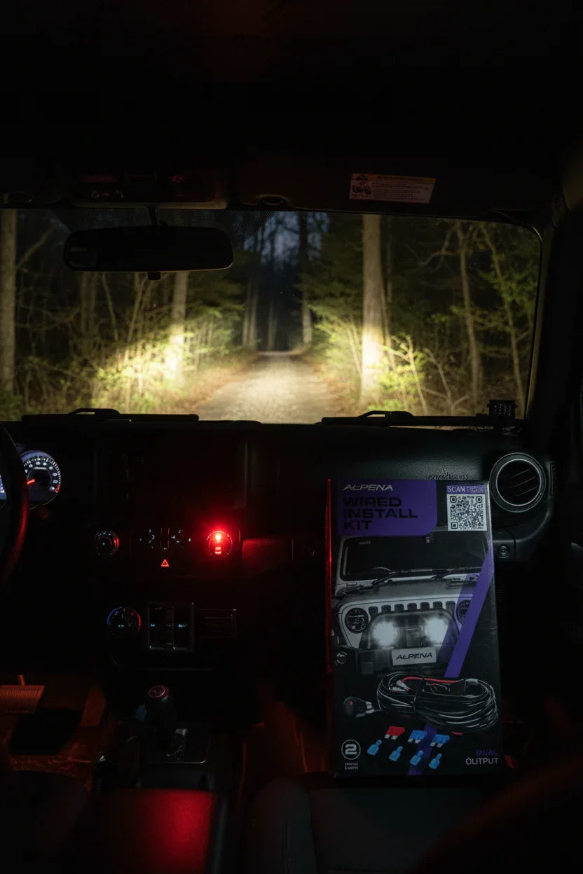Illuminated red toggle switch mounted on vehicle dashboard — Alpena auxiliary light control on night forest trail