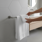 Hands hanging white luxury bath towel on modern matte steel towel bar in Scandinavian bathroom