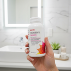 Woman holding GNC Women's Gelatin with glowing skin in bright bathroom – More4less Outlet
