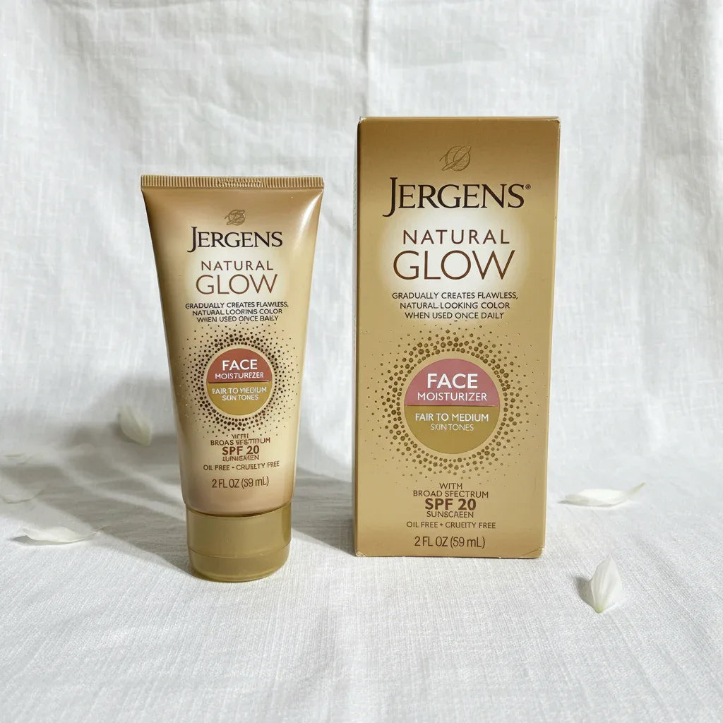 Bright airy studio composition of Jergens Natural Glow gold squeeze tube face moisturizer and box on white linen surface