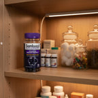 Sambucol Black Elderberry Gummies bottle inside organized medicine cabinet pantry with high-transparency apothecary storage jars and soft shelf lighting