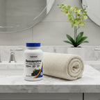 Nutricost Resveratrol bottle on white quartz bathroom vanity with rolled cotton towel and green orchid