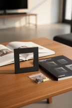 Legrand Adorne graphite wall plate on wooden interior design table next to open book and designer hardware catalogue
