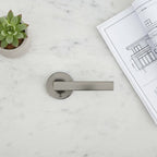 Baldwin Reserve contemporary half-dummy door lever flatlay on white marble surface with architectural blueprints