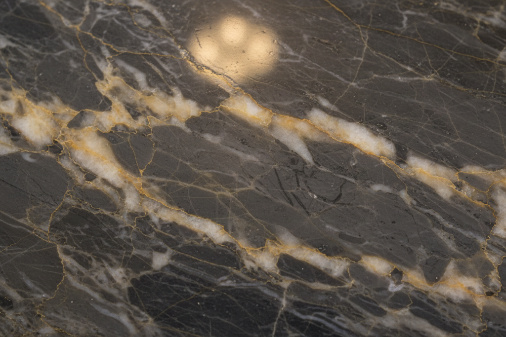 Close-up macro of polished natural stone surface with deep veining reflecting soft interior light