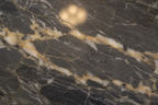 Close-up macro of polished natural stone surface with deep veining reflecting soft interior light