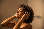 Woman with wavy coily hair lathering shampoo into wet hair in shower eyes closed relaxed self-care lifestyle photo