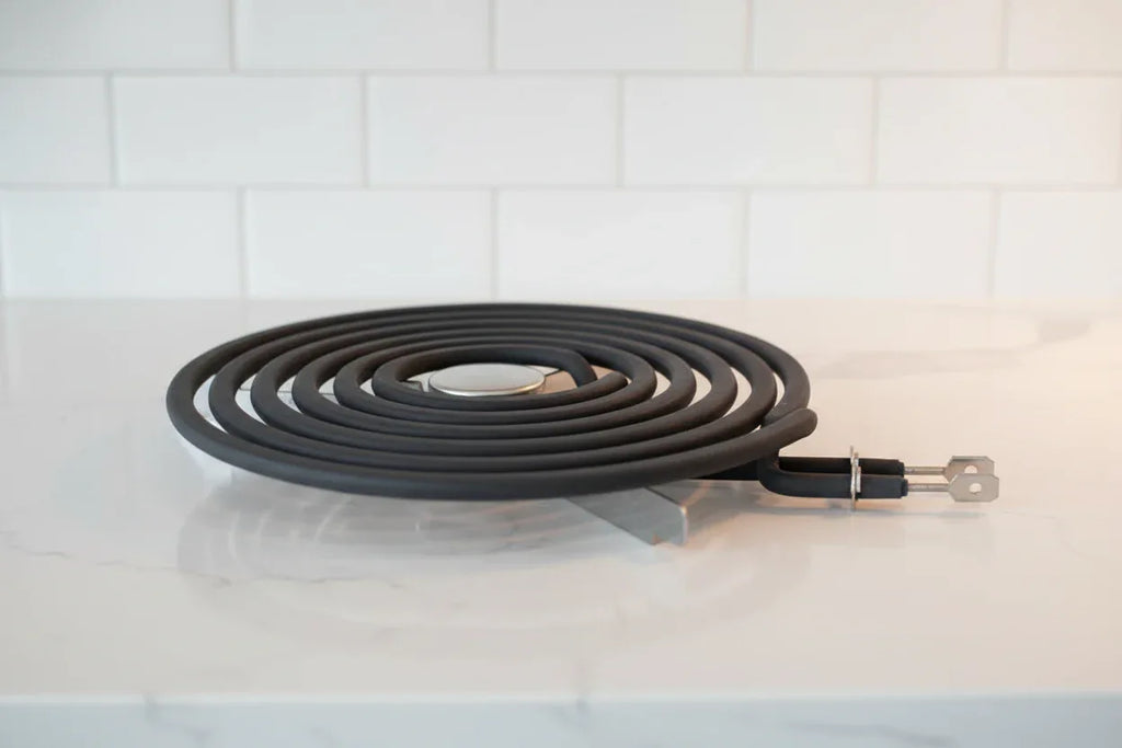 Professional close-up of a new black electric range coil burner element on a bright kitchen countertop