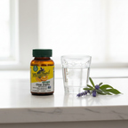 Women's vitamin supplement amber glass bottle beside water glass and fresh botanicals on white marble countertop – More4less Outlet
