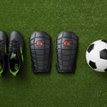 G-Form Pro-S Blade Shin Guards flat lay on soccer turf with cleats and ball