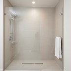 Grohe Tempesta Cosmopolitan 100 chrome shower head in a contemporary walk-in shower with beige porcelain tile and frameless glass enclosure.