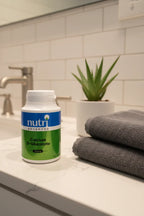 Nutri Advanced Calcium D-Glucarate on contemporary bathroom vanity with charcoal facial towels and aloe vera plant