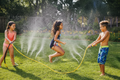 Wham-O Classic Water Jump Rope kids jumping through water spray on backyard lawn