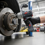 Ingersoll Rand 35MAX ultra-compact impact wrench being used by mechanic in tight wheel-well area of high-performance vehicle in modern garage