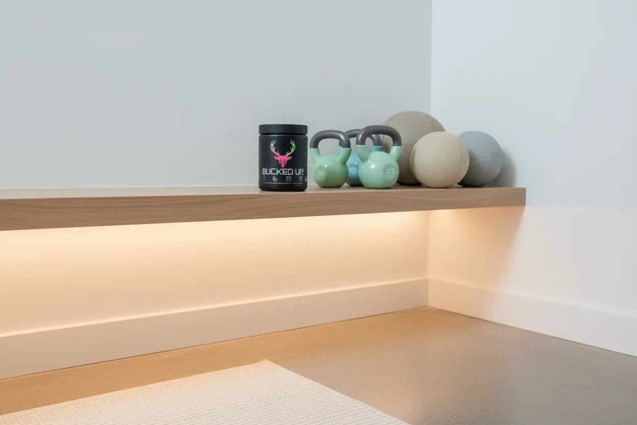 Bucked Up Pre-Workout Strawberry Kiwi on home gym shelf with kettlebells — daily fitness supplement storage
