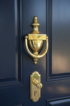 Baldwin 0102 Colonial Door Knocker Polished Brass mounted on high-gloss navy blue front door with brass handle set