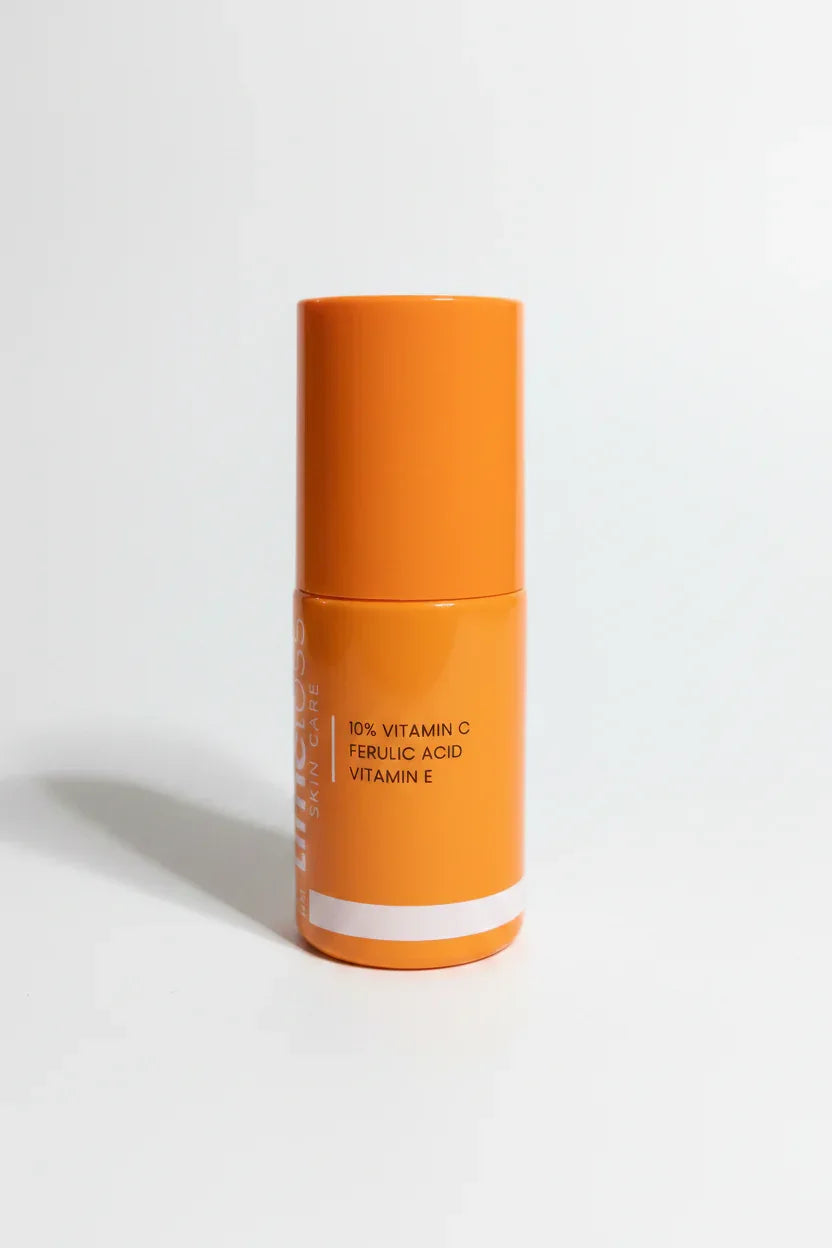 Clinical professional close-up of small orange laboratory-grade skincare serum bottle on clean white surface in bright studio lighting