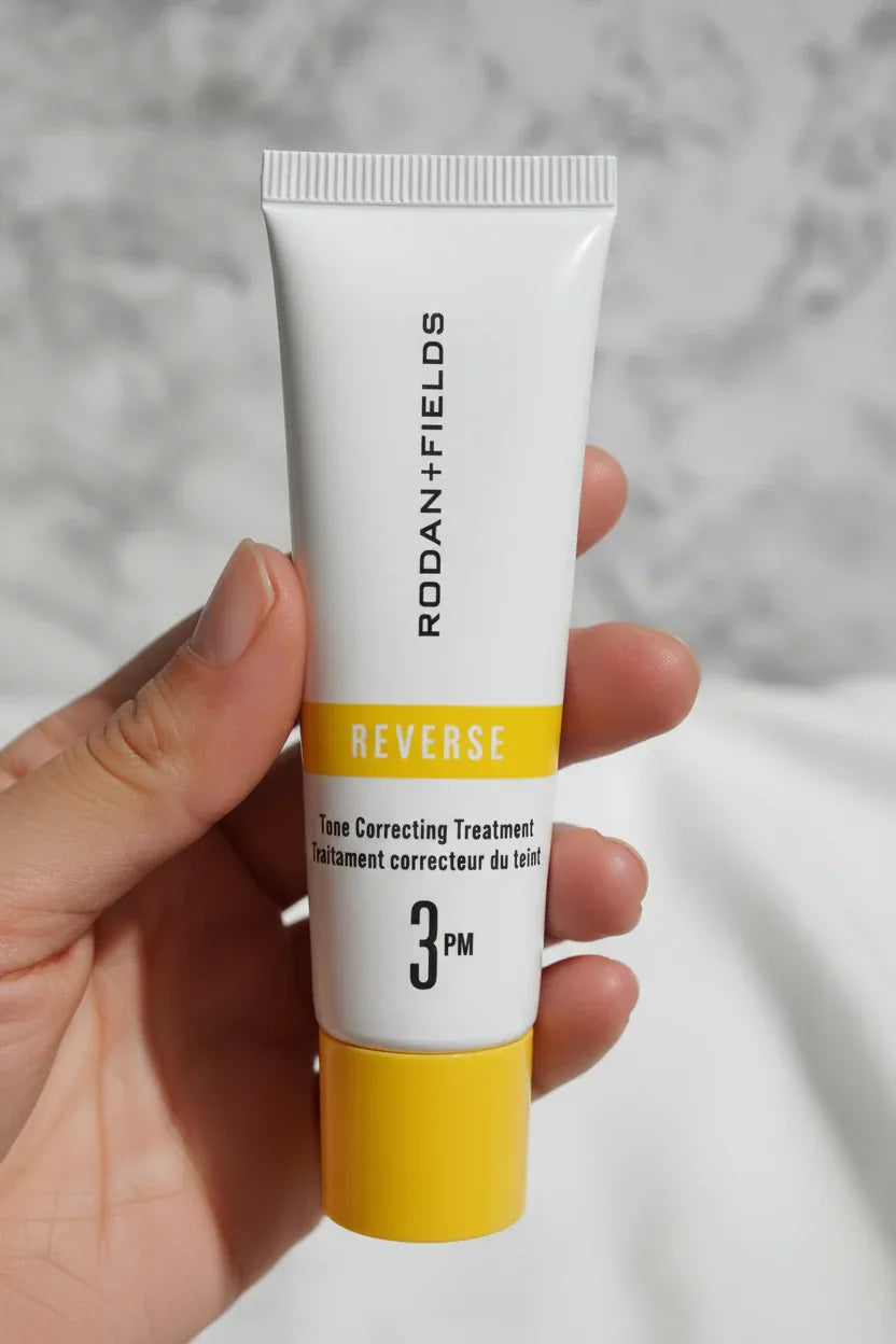 In-hand close-up of Rodan + Fields REVERSE tube showing 3PM gold label detail natural light