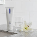 Premium ZO Skin Health Normacleanse facial wash on granite vanity with water glass and white lily purity hydration