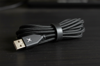 Close-up macro of Altec Lansing GM300 braided USB cable with Altec Lansing X logo connector and cord organizer clip on dark desk