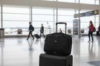 Solo New York Ace Slim Brief sliding over rolling luggage trolley handle at airport — travel-ready laptop bag — More4less Outlet