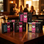 Multiple Glitter Flask Gift Set boxes on contemporary wood bar top during lounge-style event with warm golden hour lighting