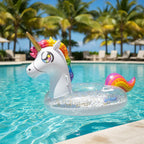 PoolCandy Glitter Unicorn pool tube floating in tropical resort pool palm trees