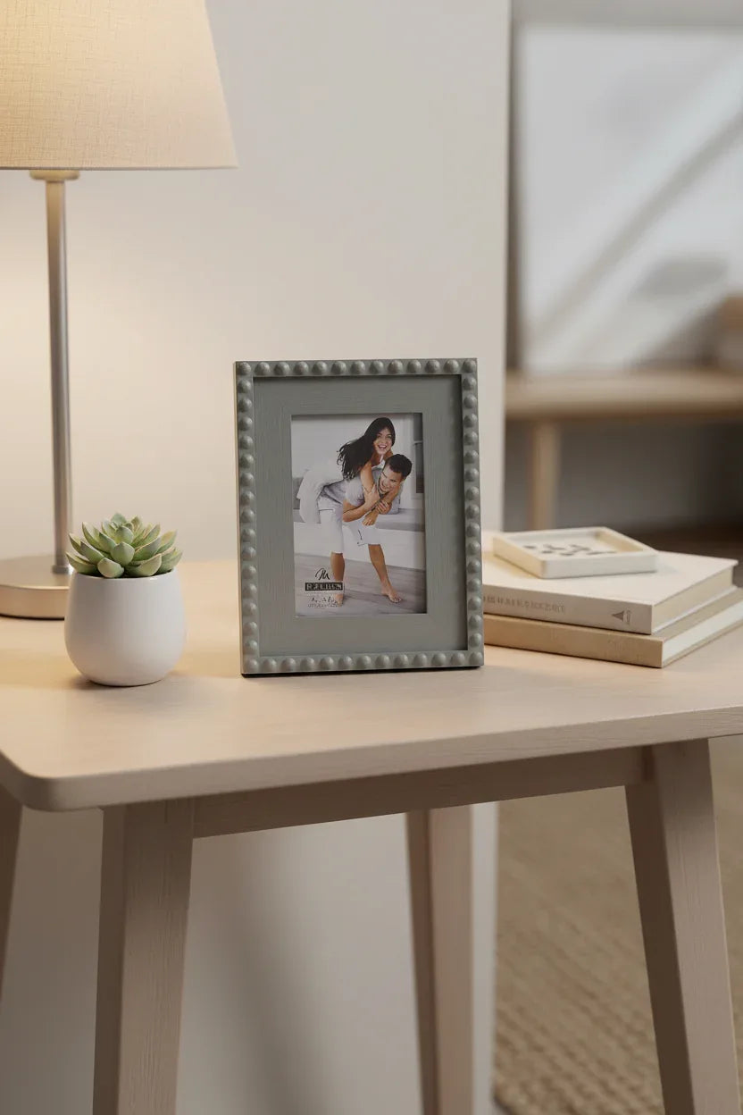 Stylish tabletop arrangement featuring the grey beaded portrait frame on a neutral colored end table