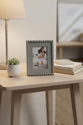 Stylish tabletop arrangement featuring the grey beaded portrait frame on a neutral colored end table