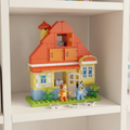 LEGO DUPLO Bluey's Family House with Memory Game (set 10459) — colorful built Heeler home with red roof, yellow walls, opening doors and windows, with Bluey, Bingo, and Chilli DUPLO figures on a bright white playroom shelf