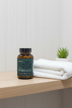 BIOMA Probiotics amber glass bottle on wooden bathroom shelf beside white towel and small succulent