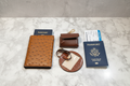 Collection XIIX brown ostrich-print passport holder croc-print luggage tag and snap headphone case flat lay with passport and boarding pass — 3-piece travel gift set