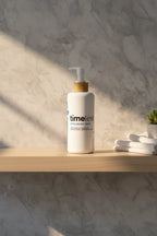 Clean minimalist bathroom shelf displaying a large white high-capacity skincare bottle with bamboo pump in soft morning light