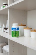 Nutri Advanced Calcium D-Glucarate on white oak shelf in organized family health closet with premium apothecary jars