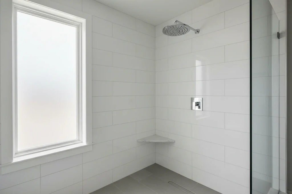 Clean modern bathroom with high-polished chrome Moen showerhead mounted on white tile wall