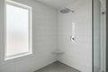 Clean modern bathroom with high-polished chrome Moen showerhead mounted on white tile wall