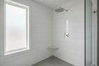Clean modern bathroom with high-polished chrome Moen showerhead mounted on white tile wall