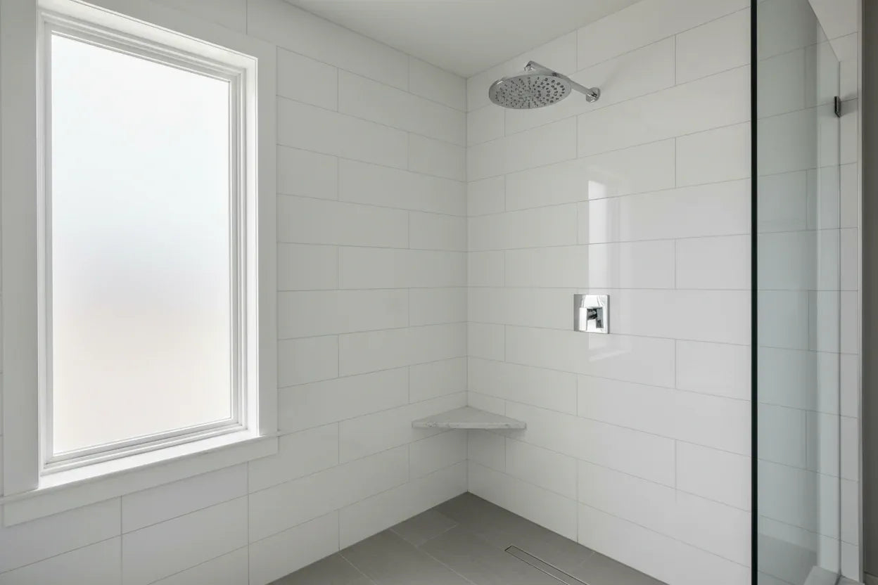 Clean modern bathroom with high-polished chrome Moen showerhead mounted on white tile wall
