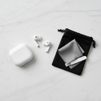 Flat lay of true wireless earbuds with charging case and earbud cleaning kit on marble surface