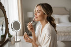 Woman blending liquid foundation with a brush at bedroom vanity mirror