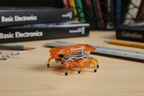 Close-up macro of HEXBUG Fire Ant orange micro robotic creature on STEM desk showing internal electronic components