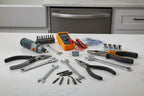 Professional appliance repair tools on a clean modern kitchen countertop near a dishwasher