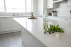 Bright modern kitchen island with white quartz countertop featuring a plant-based cleaning spray bottle and fresh verbena sprigs
