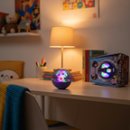 Bitzee Hamster Ball interactive digital pet toy displayed on a childs wooden desk with warm bedroom lighting and pixel-art hamster packaging visible nearby