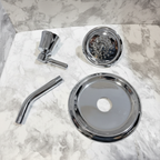Moen Dartmoor chrome shower trim kit components flat lay on white marble showing shower head arm and escutcheon
