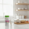 Rainbow Light Women's One Multivitamin bottle on minimalist kitchen breakfast bar with glass of water and whole-grain breakfast tray