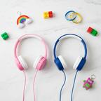 Flat lay overhead of pink and blue kids over-ear wired headphones side by side on white marble surface