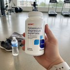 GNC Potassium & Magnesium Aspartate bottle in gym setting with water bottle and gear – More4less Outlet