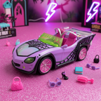 Purple Monster High Ghoul Mobile toy car on a pink and purple glittery surface with Monster High doll accessories scattered around it.